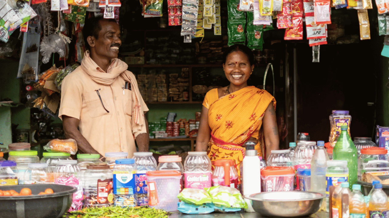 Two people standing in a small kiosk smiling