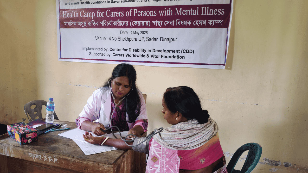 two people sitting a table one taking the others blood pressure