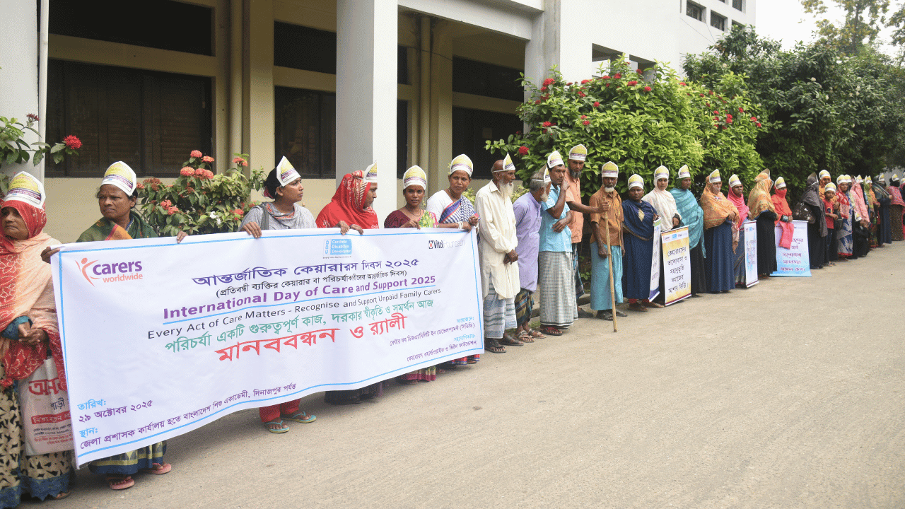 People lining the side of a road some of them holding a large banner