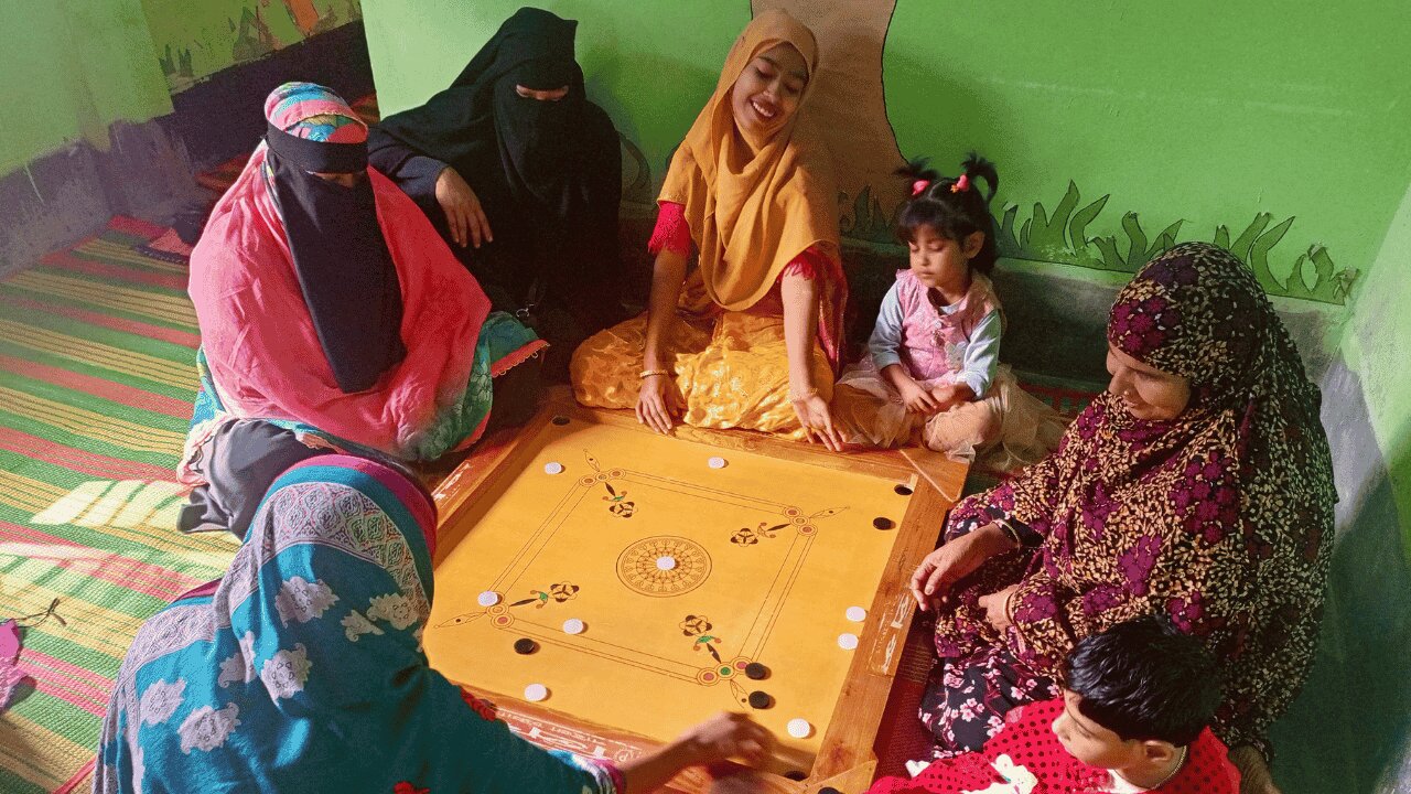 Group of women and children sitting on the floor playing a board game