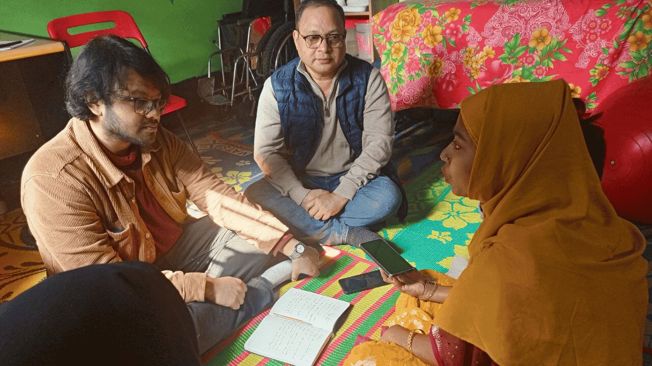 Four people sitting on the floor inside talking