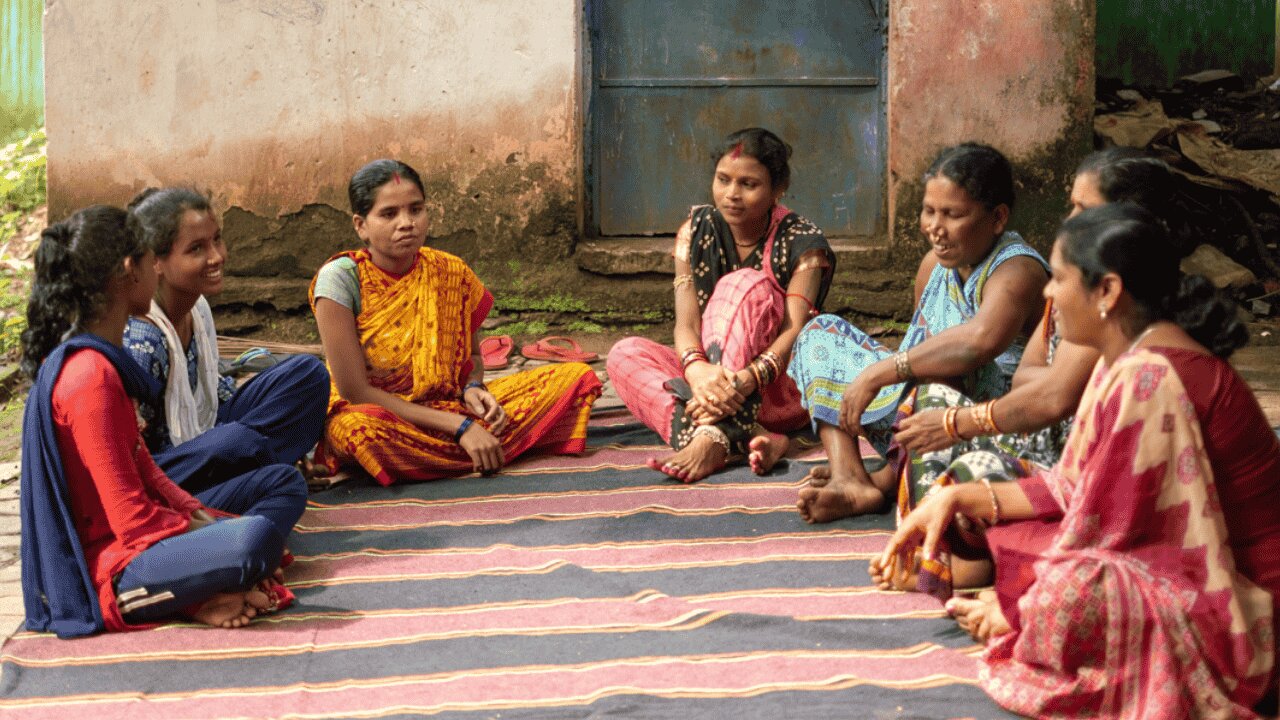 A group of women sitting on the floor in a circle talking