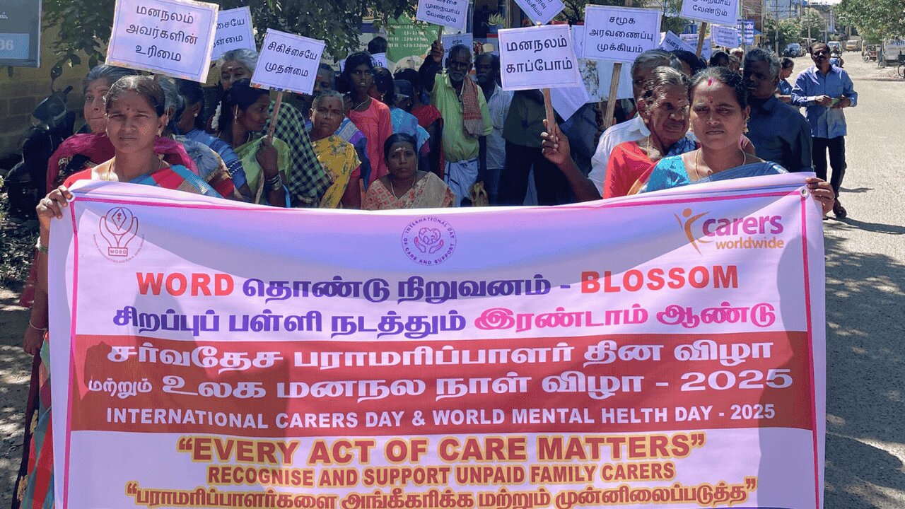 A group of poeple standing outside behind a large banner reading international carers day every act of care matters
