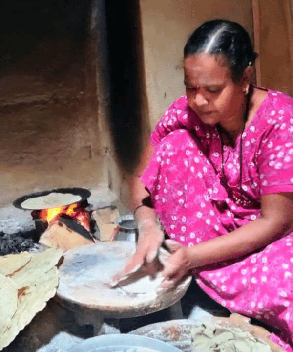 An image of of a woman sitting on the floor making roti