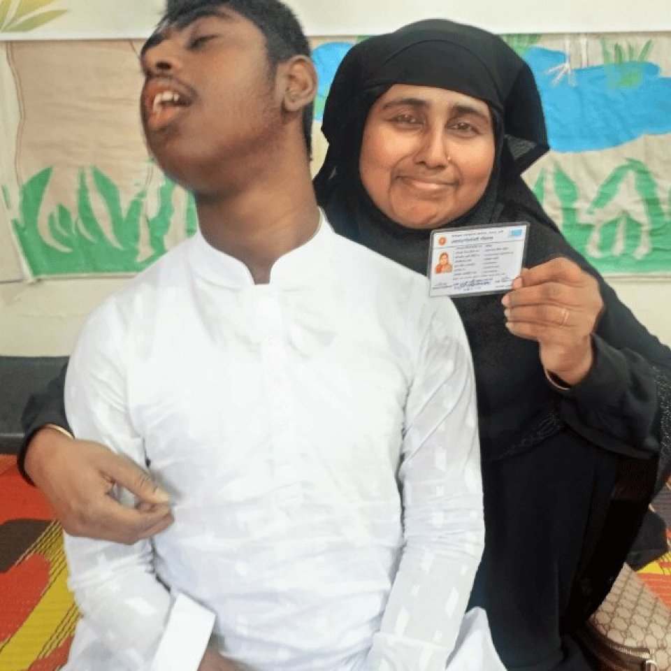 Image of a woman holding up an ID card with her arm around her child