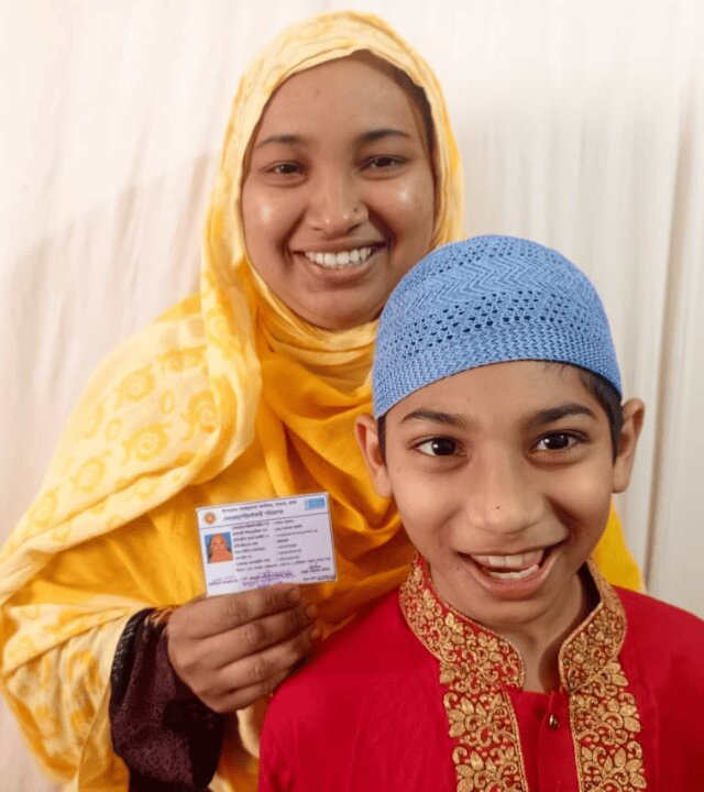 Image of a woman holding up an ID card with her child sitting in front of her