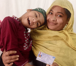 Takiya Alt Text Image Of A Woman Holding Up An Id Card With Her Arm Around Her Child