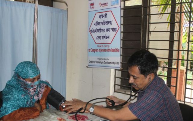 Doctor conducting health check on female carer in Bangladesh