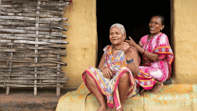 Two women sitting in a doorway one combing the others hair