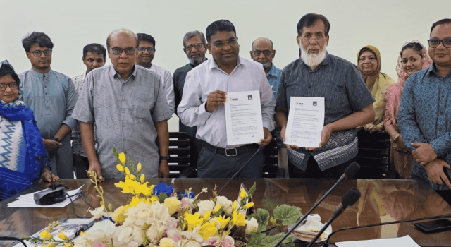 Group of people standing behid a desk holding up copies of a signed agreement