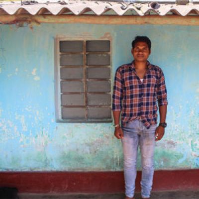 Male carer stood outside his house in India