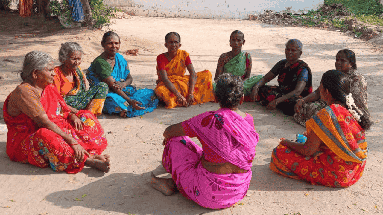 Group of women sitting outside on the floor in a circle talking