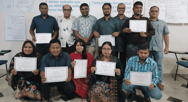 Group of people standing and kneeling in a group inside each holding up a certificate
