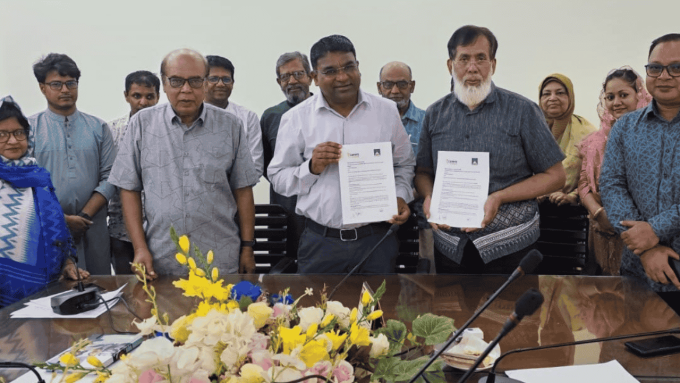 Group of people standing behid a desk holding up copies of a signed agreement