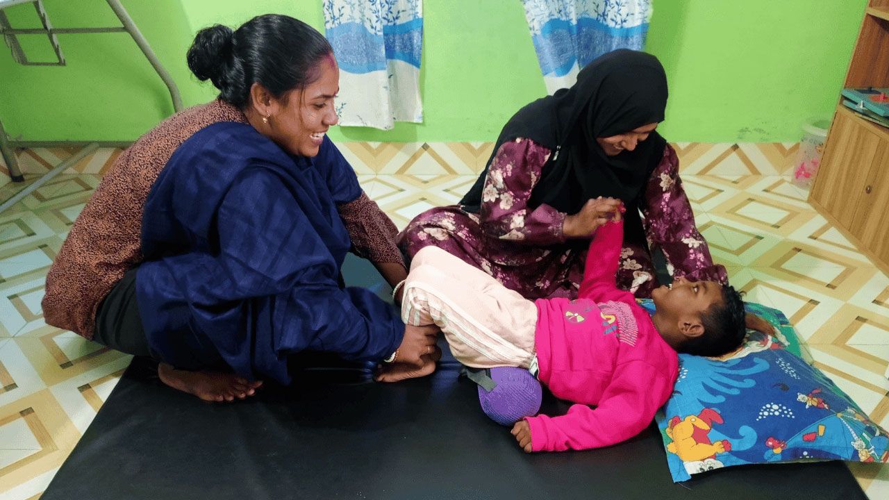 Two women helping a child with physiotherapy